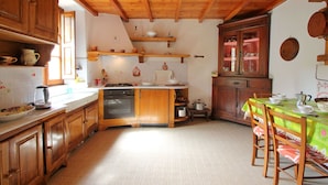 Una cocina con armarios de madera, una estufa y un comedor con mesa y sillas.