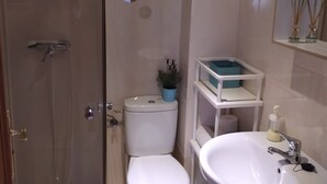 Ein Badezimmer mit Duschkabine, Toilette, Waschbecken und Spiegel.