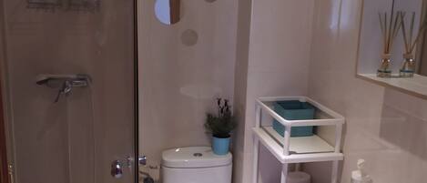 Ein Badezimmer mit Duschkabine, Toilette, Waschbecken und Spiegel.