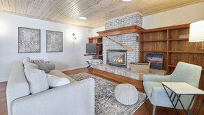 A living room with a fireplace, a sofa, a chair, and a TV.