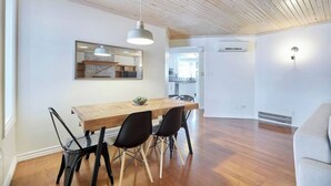 A modern kitchen with white cabinets, a wooden dining table, and black chairs.