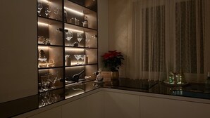 A modern kitchen with a glass-fronted wine cabinet, a potted plant, and a dining area with a table set for two. - LUXURY WELLNESS PENTHOUSE KADENA WITH DREAM SEE VIEW (Zadar)