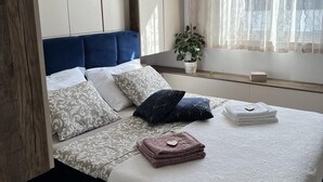 A modern bedroom with a large bed, a blue headboard, and a hanging light fixture. - LUXURY WELLNESS PENTHOUSE KADENA WITH DREAM SEE VIEW (Zadar)