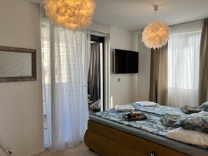 A bedroom with a bed, curtains, a television, and a chandelier. - LUXURY WELLNESS PENTHOUSE KADENA WITH DREAM SEE VIEW (Zadar)