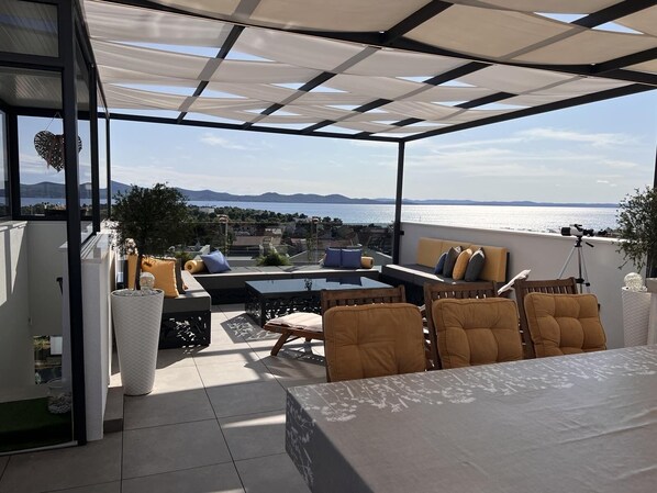 Una terraza con vista al mar, amoblada con sofás y una mesa, y un telescopio.