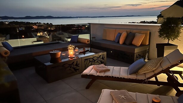 A rooftop terrace with a sofa, lounge chairs, and a table with candles. - LUXURY WELLNESS PENTHOUSE KADENA WITH DREAM SEE VIEW (Zadar)