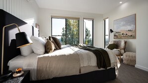 Une chambre moderne avec un grand lit, une table de chevet, une lampe sur pied et un tableau au mur.