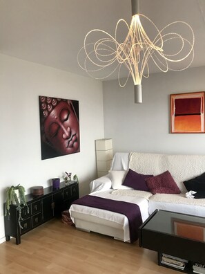 Um quarto moderno com cama, mesas de cabeceira, escrivaninha e luminária suspensa.