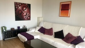 A living room with a sectional sofa, a glass coffee table, a dark wooden cabinet, and two wall-mounted paintings. - Central and large apartment with sea views (Las Palmas de Gran Canaria)