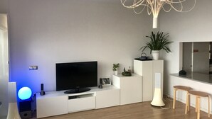 A modern living room with a flat-screen TV, white cabinetry, a plant, and a unique ceiling light fixture. - Central and large apartment with sea views (Las Palmas de Gran Canaria)