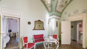 A room with a white sofa, two red chairs, a white table, and a chandelier.