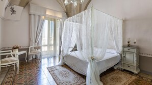 A bedroom with a four-poster bed, a nightstand, a chair, and a table with a vase of flowers. - 3267 Casa Romantica by Barbarhouse (Sava)