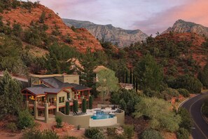 A two-story house with a swimming pool, surrounded by a mountainous landscape.