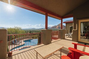 Varanda com piscina, grades vermelhas e vista para montanhas.