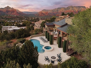 A residential property with a swimming pool, outdoor seating, and a view of red rock formations.