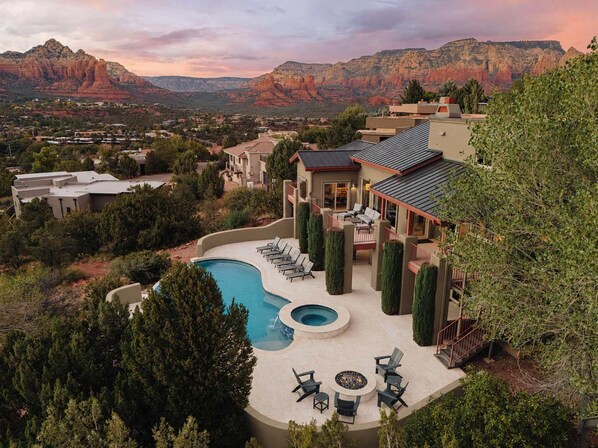 A residential property with a swimming pool, outdoor seating, and a view of red rock formations.