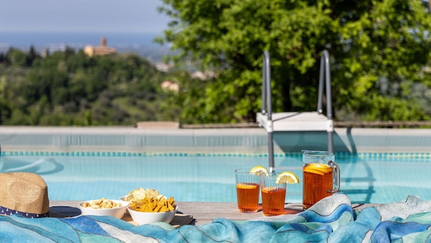 Ein Poolbereich mit Tisch, Chipschalen, Teegläsern und Blick auf Meer und Bäume.