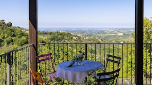 Ein Balkon mit Tisch und Stühlen, der einen schönen Ausblick auf eine Landschaft mit Gebäuden und Grünflächen bietet.