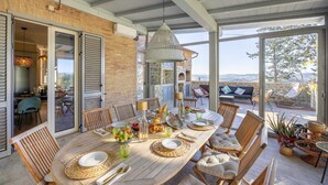 Un patio amplio con una mesa de madera lista para comer, rodeado de sillas de mimbre y un muro de piedra.