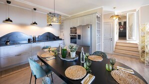 Una cocina moderna con armarios blancos, una isla central e iluminación colgante.