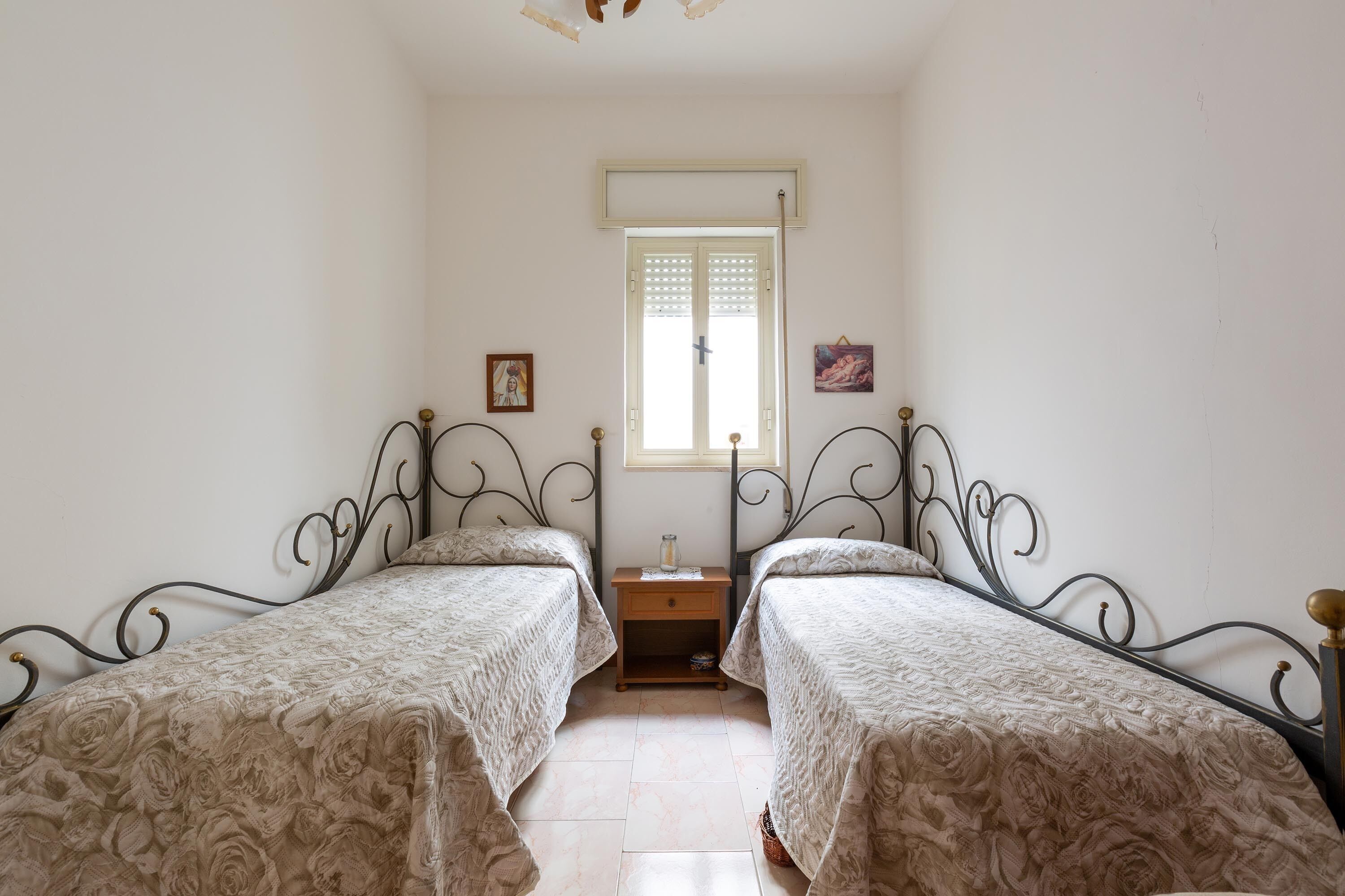 Un dormitorio con dos camas, una mesita de noche, una ventana y una pequeña mesa.
