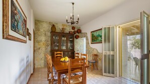 A dining area with a wooden table, chairs, a chandelier, and a stone wall. - 3266 Villetta Delle Viole by Barbarhouse (Torricella)