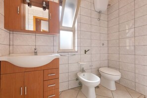 A bathroom with a wooden vanity, a sink, a bidet, and a toilet.