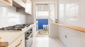 A narrow kitchen with white cabinets, a stove, and a blue wall in the background. - 3268 Casa Doria by Barbarhouse (Alessano)