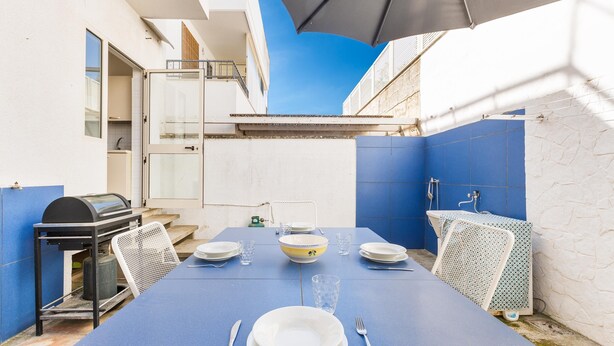 A dining area with a blue table set for four, a grill, and a view of the sky. - 3268 Casa Doria by Barbarhouse (Alessano)