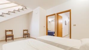 A bedroom with two beds, a staircase, and two wooden chairs. - 3268 Casa Doria by Barbarhouse (Alessano)