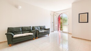 A spacious living room with a green leather sofa, a tiled floor, and a door leading to a balcony. - 3268 Casa Doria by Barbarhouse (Alessano)