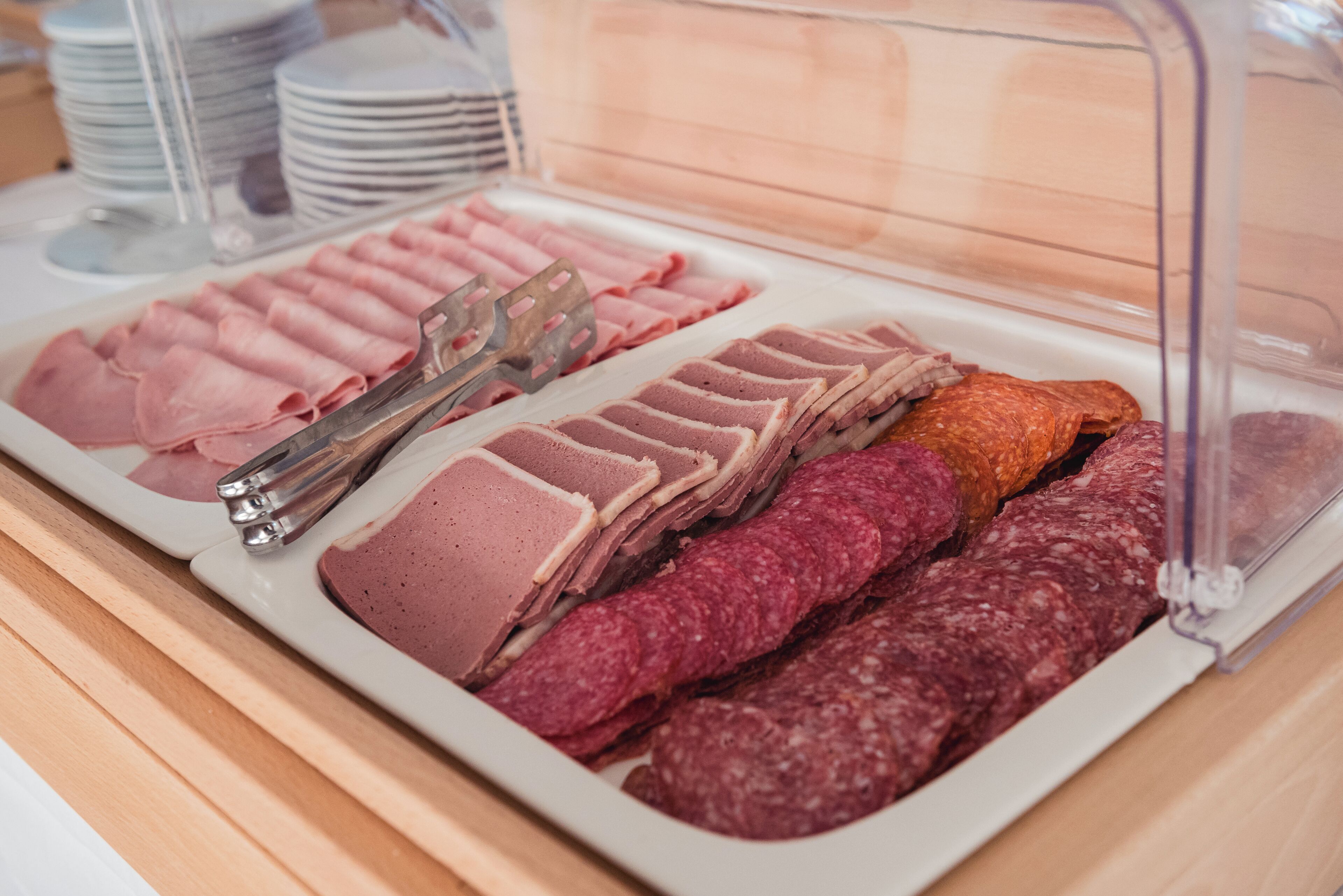 Un bufé con diversas carnes, incluyendo jamón en rodajas, salami y otras preparaciones frías.
