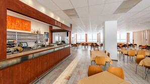 A spacious cafeteria with a bar area, multiple tables, and chairs. - HOTEL AGRI Soběšice (Sobešice)