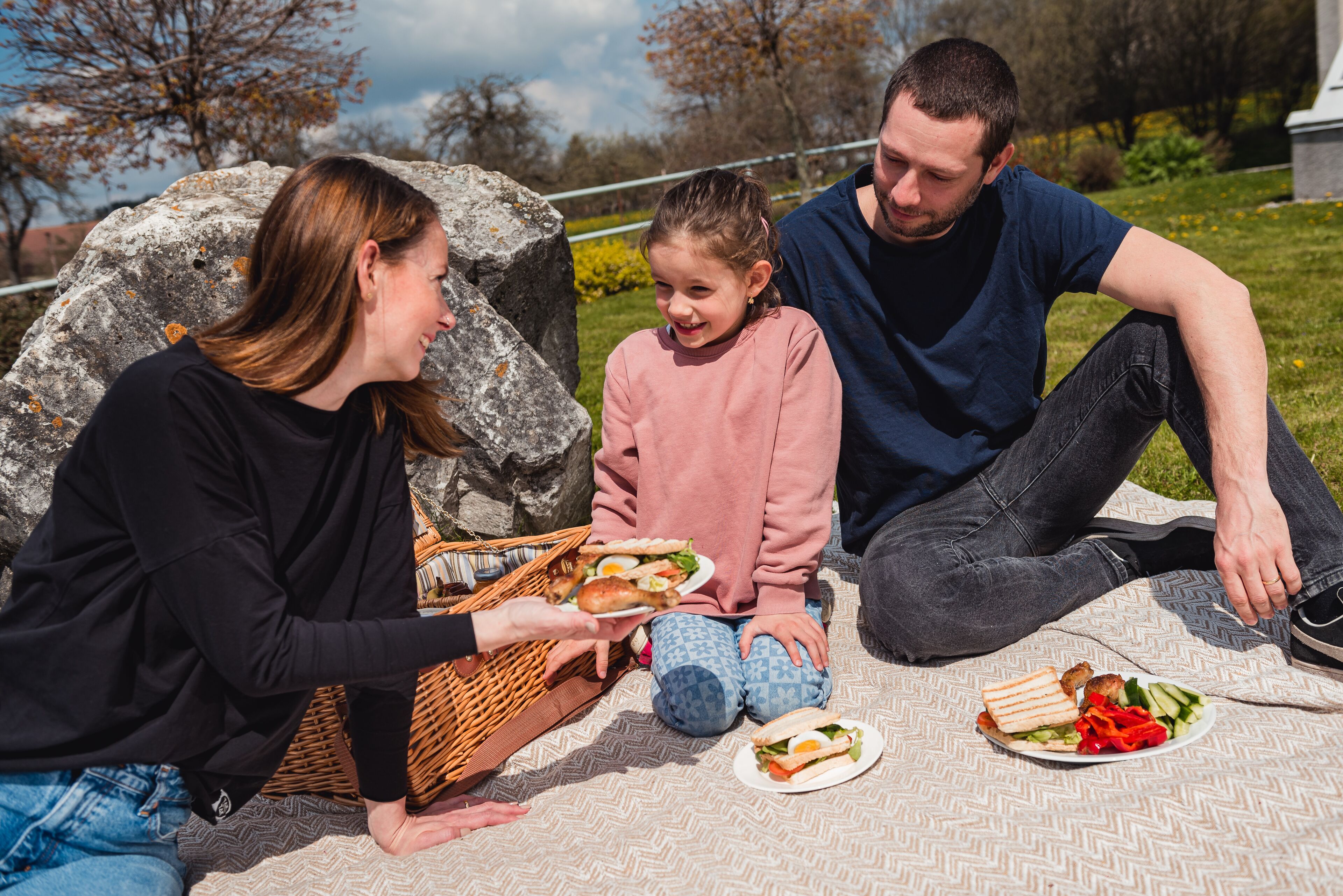 Ein Familienpicknick mit Sandwiches und einem Esskorb auf einer Decke.