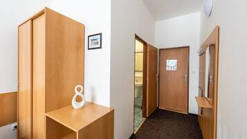 A hallway with wooden wardrobes, a small white shelf, and a framed certificate on the wall.