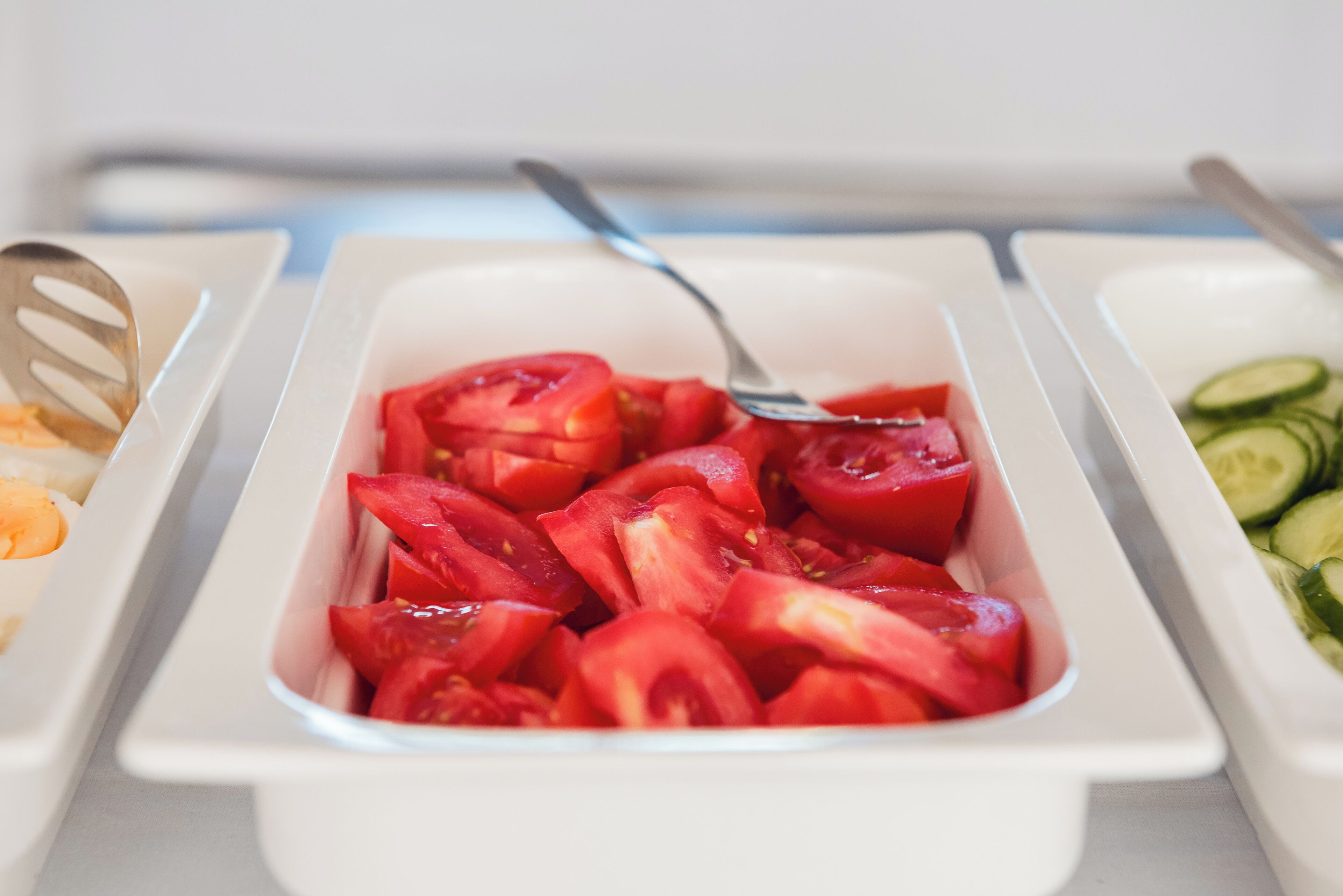 Un bufé con una variedad de frutas cortadas, incluyendo tomates y pepinos.