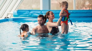 A swimming pool with clear blue water, a blue poolside area, and a white fence in the background. - HOTEL AGRI Soběšice (Sobešice)