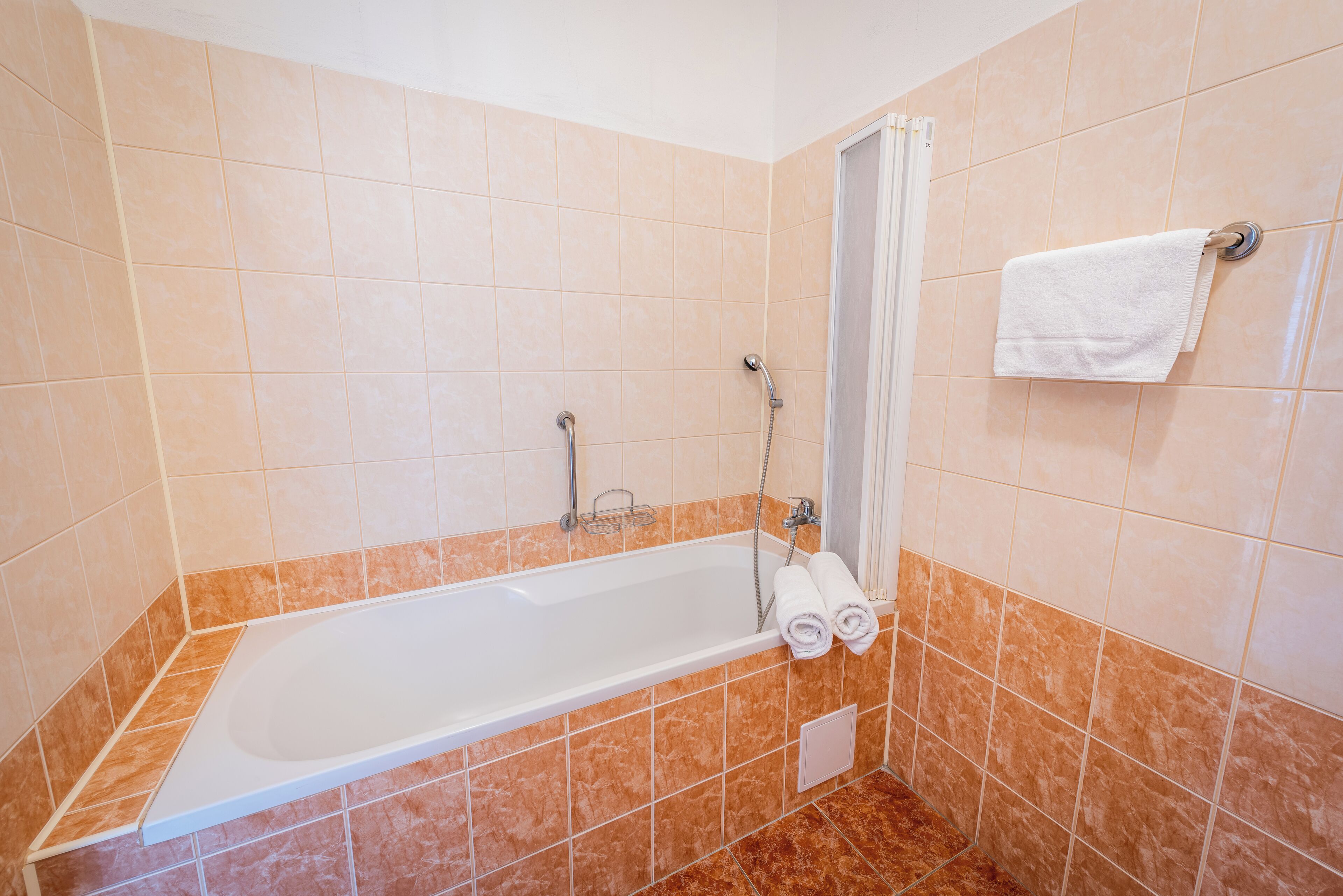 Une salle de bain avec une baignoire blanche, une douche et un porte-serviettes avec deux serviettes.