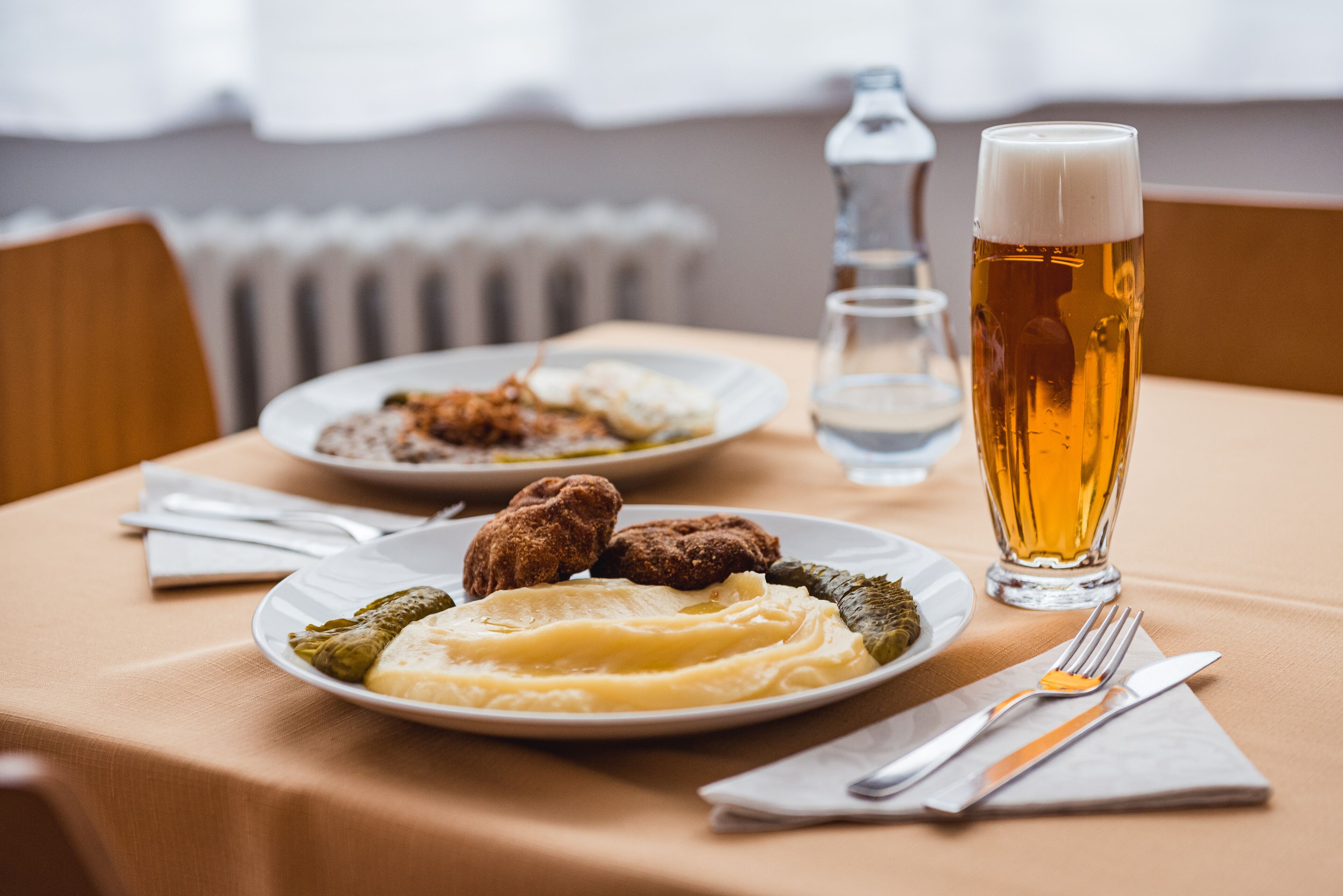 Une table avec des assiettes de nourriture, un verre de bière et des couverts.