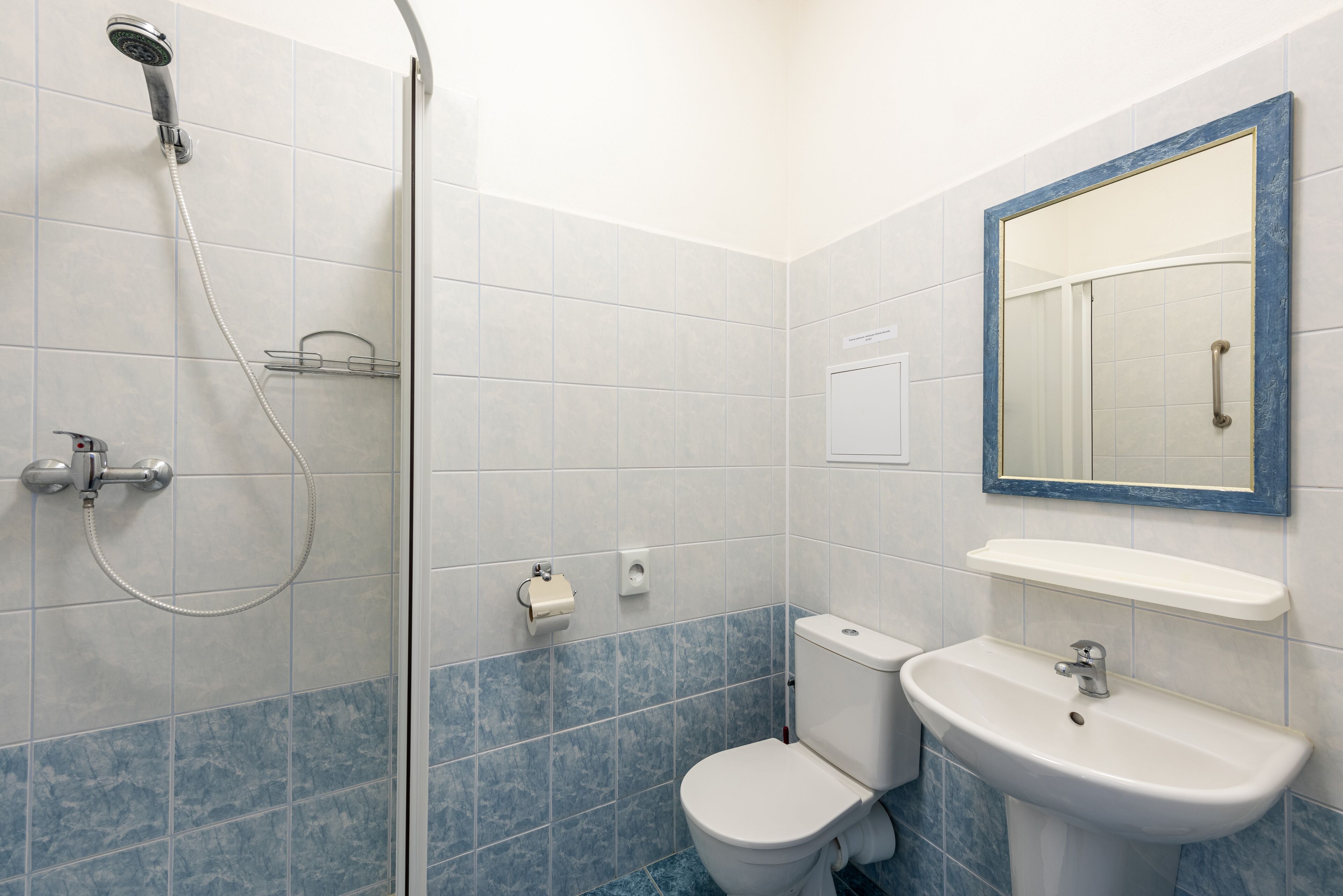 A bathroom with a shower, toilet, sink, and a mirror.