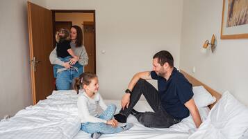 Un dormitorio con una cama, una puerta y una lámpara fijada a la pared.