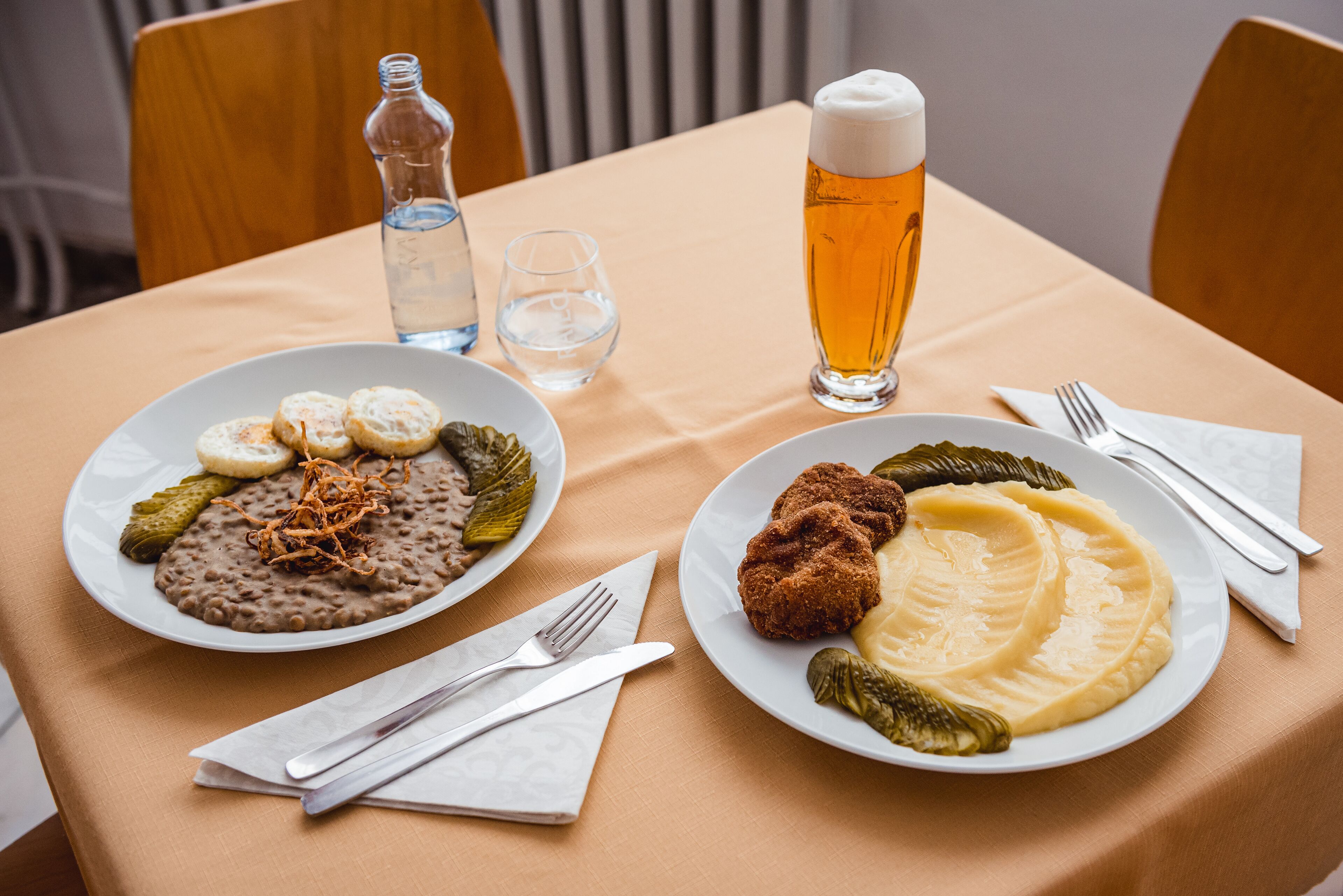 Deux assiettes de nourriture, une bouteille et des verres sont posés sur une table.
