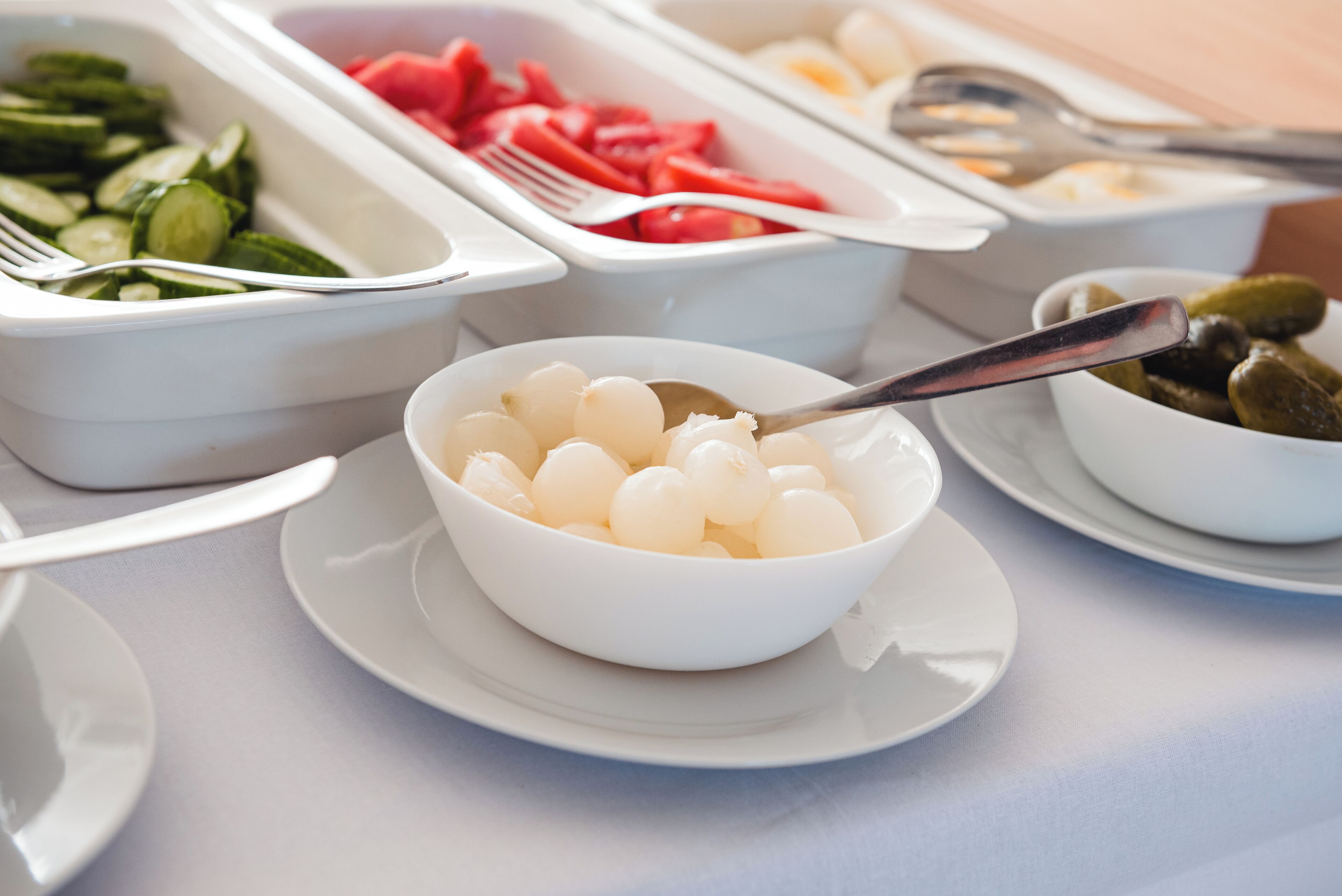 A buffet table with various food items including sliced cucumbers, watermelon, and pickles.