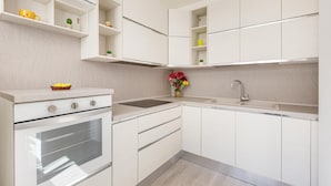 A modern kitchen with white cabinetry, a built-in oven, and a sink.
