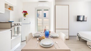 A compact room with a kitchenette, dining area, and a bed.