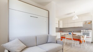 A modern living room with a sofa and a dining area with a table and chairs.