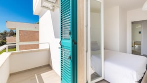 A balcony with a view of a brick building, a white room with a bed and a sliding door. - 3274 Residence Amida - Appartamento Sole by Barbarhouse (Maruggio)