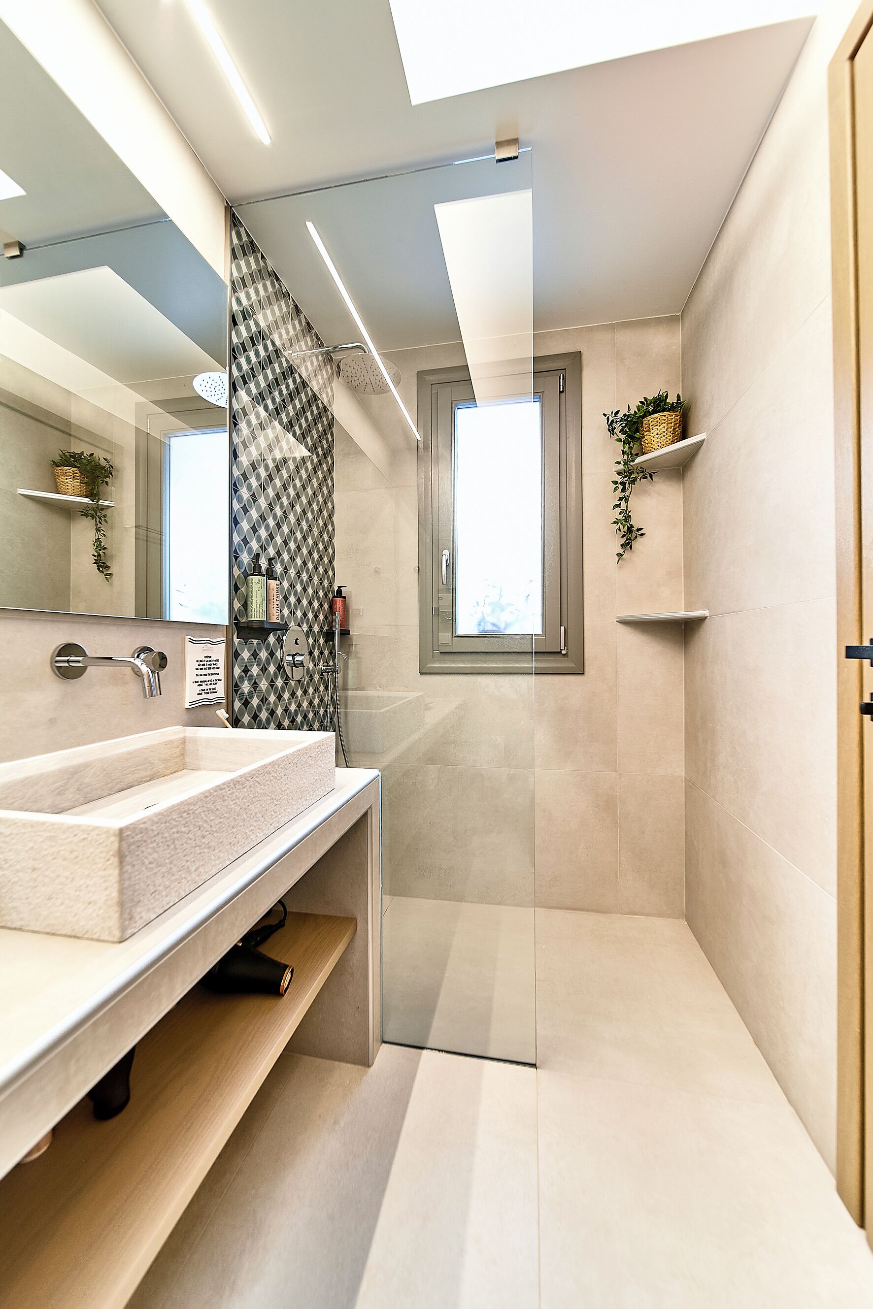 Un bany modern amb un mirall gran, un lavabo i una zona de dutxa.