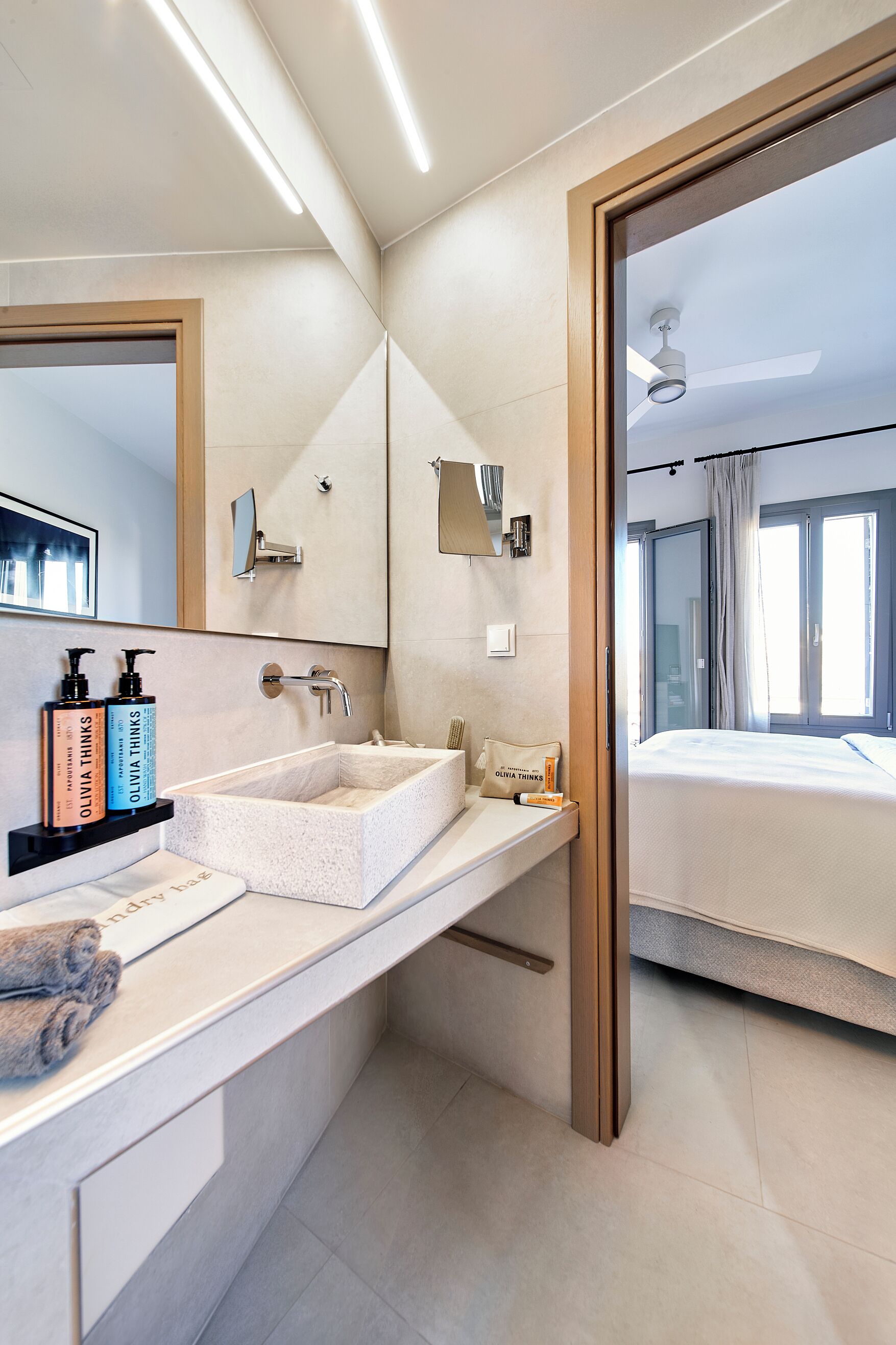 A modern bathroom with a large mirror, a white sink, and a shower area.