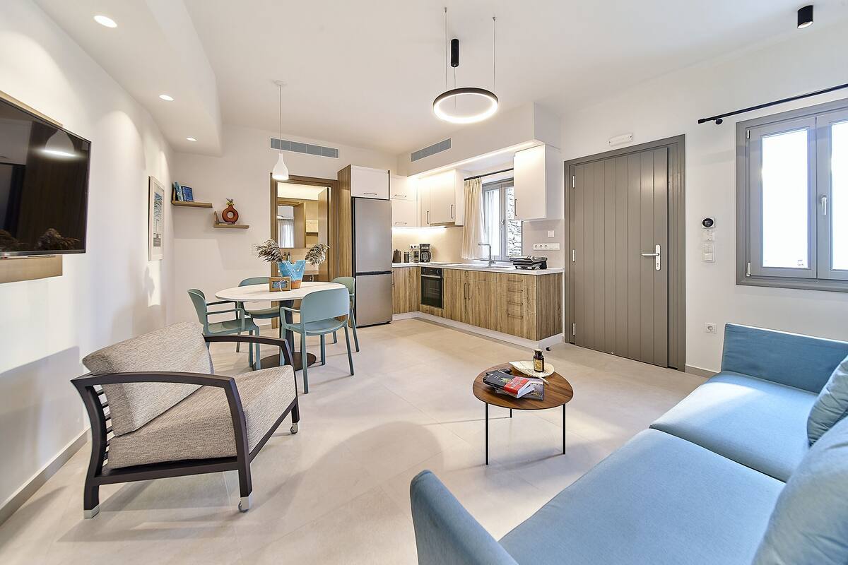 A modern living room with a sofa, a coffee table, and a dining area with chairs and a table.